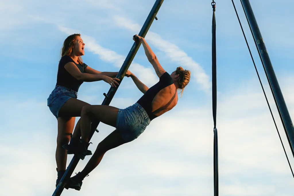 Photo de deux acrobates accrochées à une structure métallique