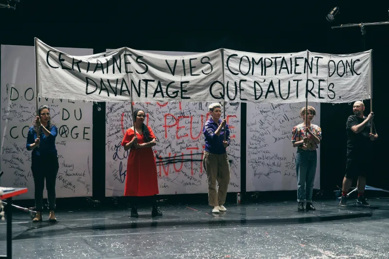 Photo de cinq comédiens qui tiennent une grande banière