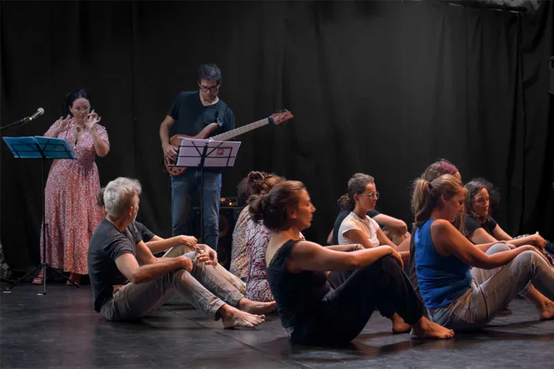 Une lectrice, un guitariste et des personnes assises au sol