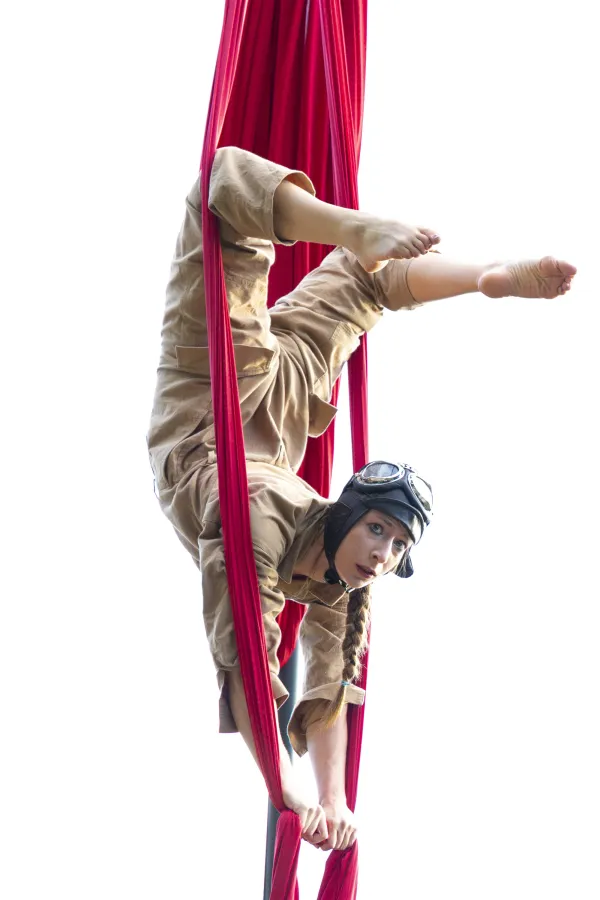 Une femme acrobate habillée en aviatrice en suspension. 