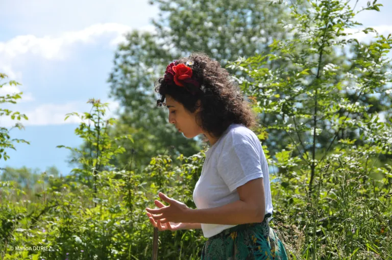 Photo d'une comédienne qui parle, entourée de verdure