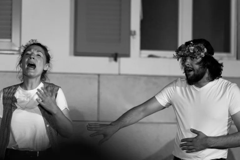 Photo en noir et blanc de deux comédiens. L'un cri, l'autre tend une main vers lui.