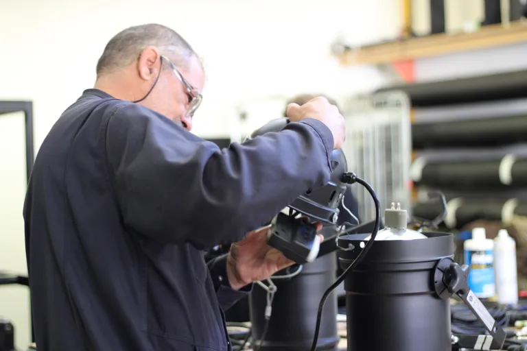 Photo d'un technicien contrôlant la douille d'un projecteur. 