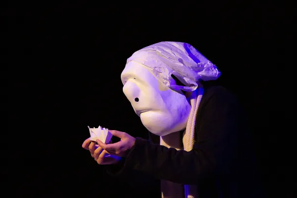 Photo d'un personnage tenant un élément en papier dans ses mains.